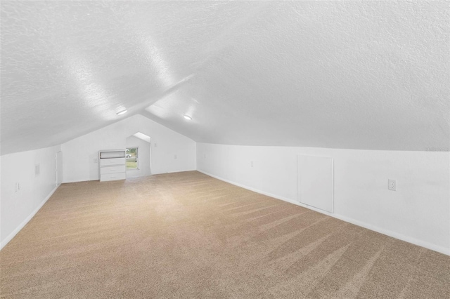 additional living space with a textured ceiling, carpet floors, and lofted ceiling