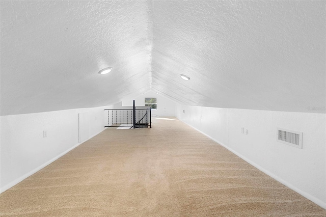 bonus room with light carpet, a textured ceiling, and vaulted ceiling