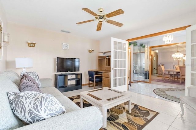 tiled living room featuring french doors and ceiling fan with notable chandelier