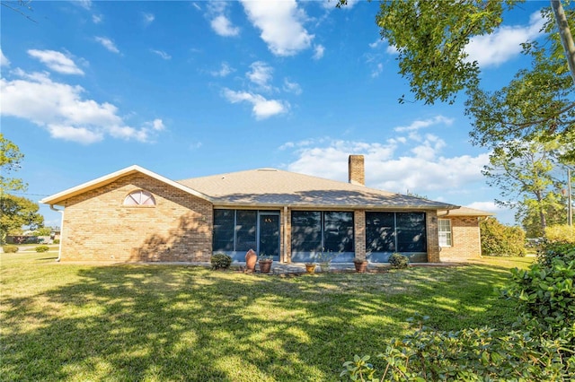 rear view of house featuring a sunroom and a yard