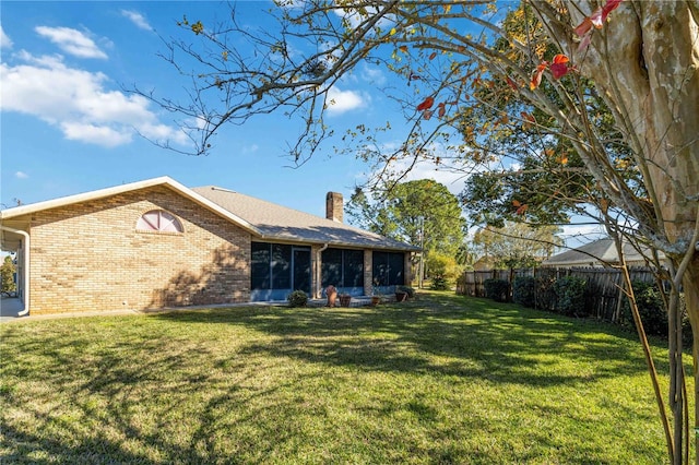 rear view of house with a sunroom and a yard