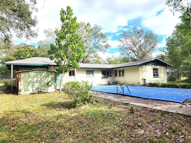 back of house featuring a lawn and a covered pool