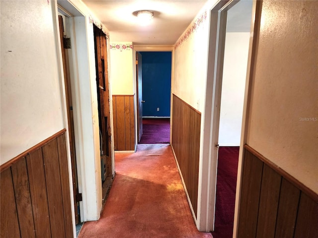 hall with dark carpet and wooden walls