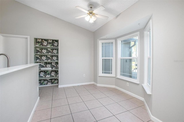 tiled empty room featuring ceiling fan, lofted ceiling, and a textured ceiling