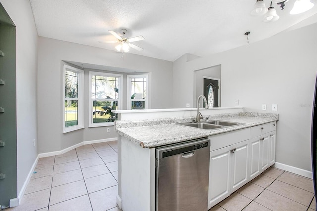 kitchen with sink, light tile patterned floors, stainless steel dishwasher, kitchen peninsula, and white cabinets