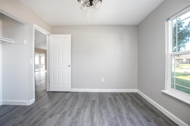 spare room with a healthy amount of sunlight, a textured ceiling, and dark hardwood / wood-style floors