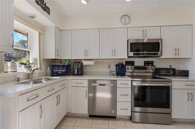 kitchen featuring white cabinetry, sink, light tile patterned flooring, and appliances with stainless steel finishes