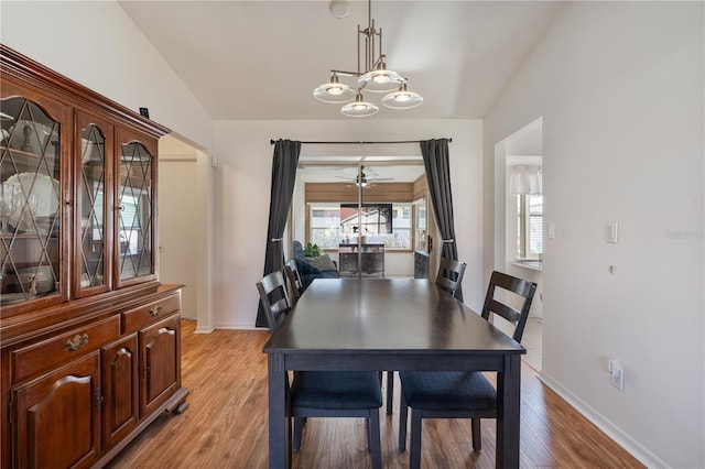 dining room with ceiling fan, lofted ceiling, and light wood-type flooring