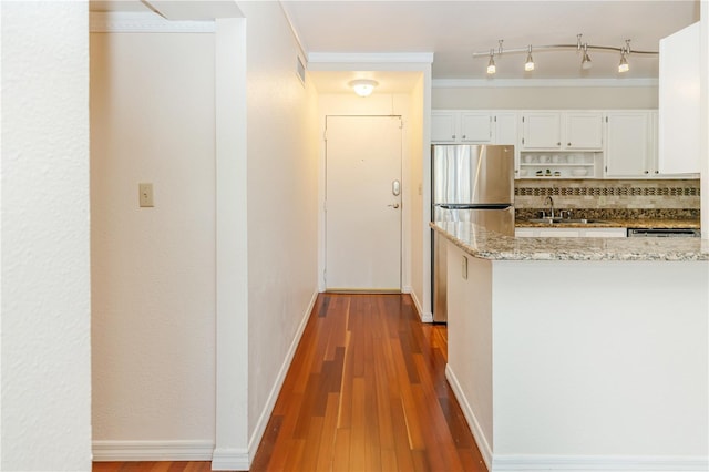 kitchen featuring stainless steel refrigerator, sink, light stone counters, decorative backsplash, and white cabinets