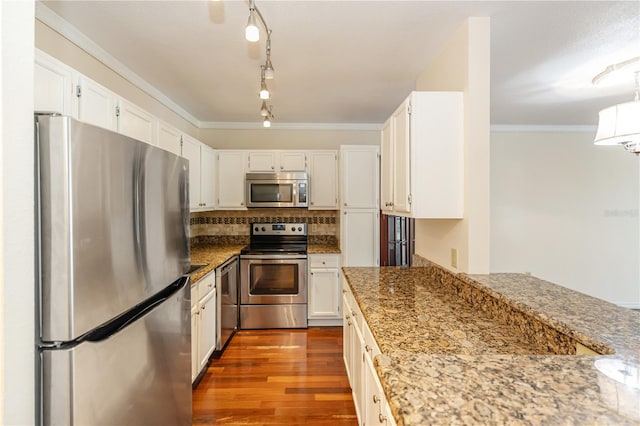 kitchen featuring light stone countertops, appliances with stainless steel finishes, tasteful backsplash, ornamental molding, and white cabinets