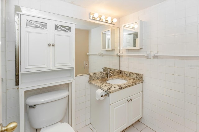 bathroom with tile patterned flooring, vanity, tile walls, and toilet