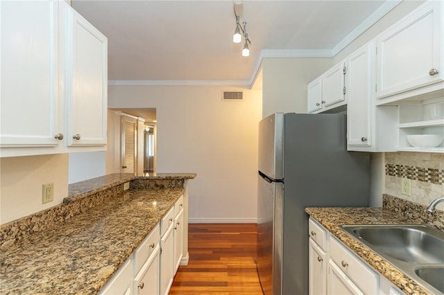 kitchen with sink, dark wood-type flooring, dark stone countertops, crown molding, and white cabinets