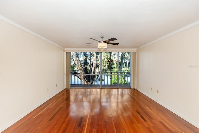 unfurnished room featuring hardwood / wood-style flooring, ceiling fan, expansive windows, and ornamental molding