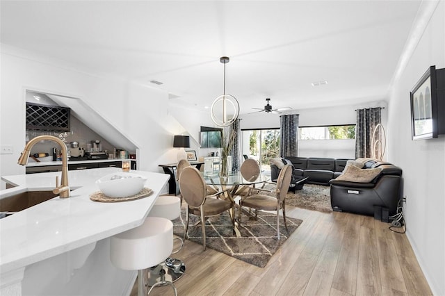 dining area featuring light hardwood / wood-style flooring, ceiling fan, ornamental molding, and sink