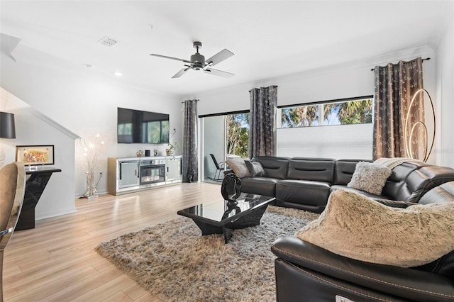 living room with light wood-type flooring, baseboards, visible vents, and a ceiling fan