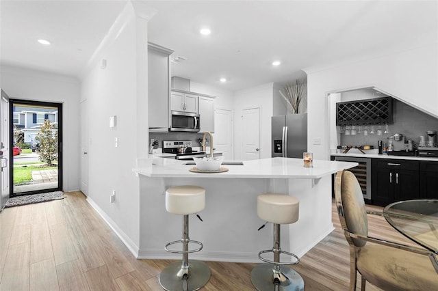 kitchen featuring a kitchen breakfast bar, backsplash, stainless steel appliances, and beverage cooler