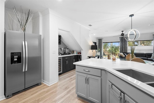 kitchen featuring pendant lighting, stainless steel refrigerator with ice dispenser, wine cooler, light hardwood / wood-style flooring, and ceiling fan