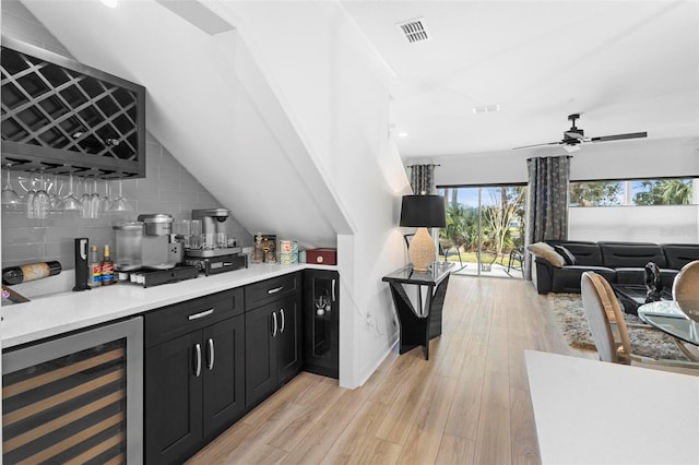 bar featuring decorative backsplash, ceiling fan, light hardwood / wood-style floors, wine cooler, and lofted ceiling