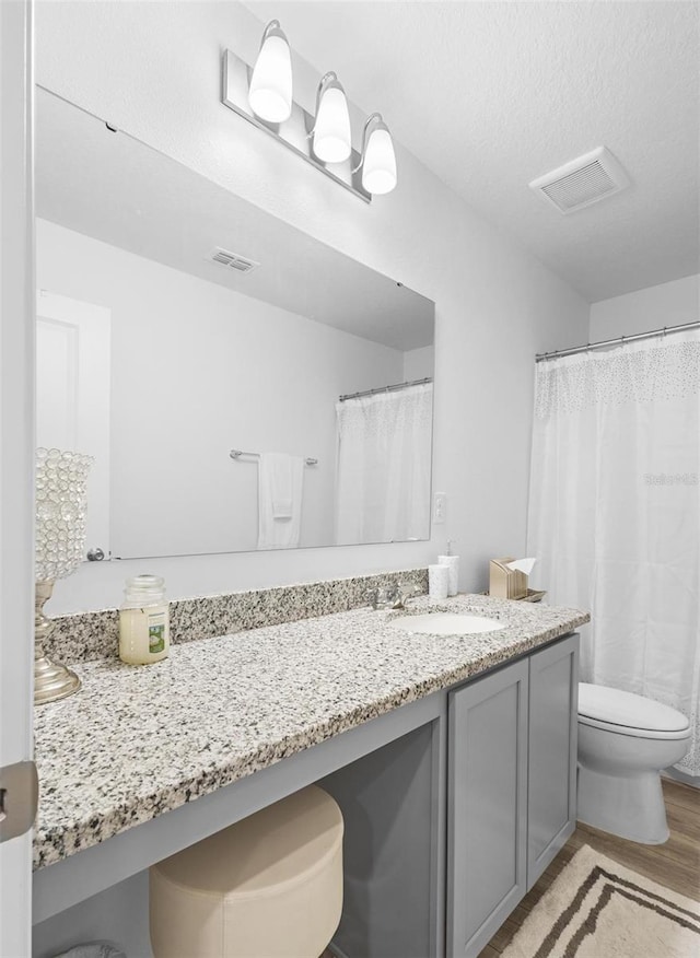 bathroom featuring hardwood / wood-style flooring, vanity, toilet, and a textured ceiling