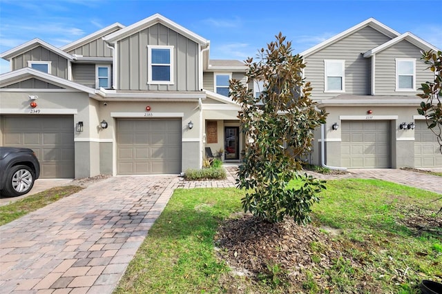 multi unit property with board and batten siding, decorative driveway, a garage, and stucco siding