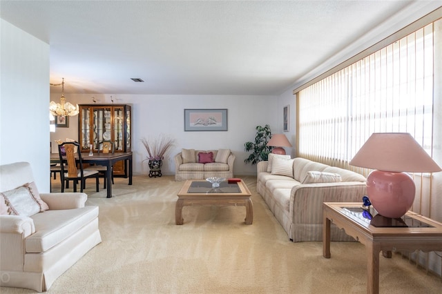 carpeted living room featuring an inviting chandelier