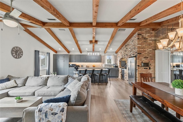 living room featuring ceiling fan with notable chandelier, hardwood / wood-style floors, and vaulted ceiling with beams