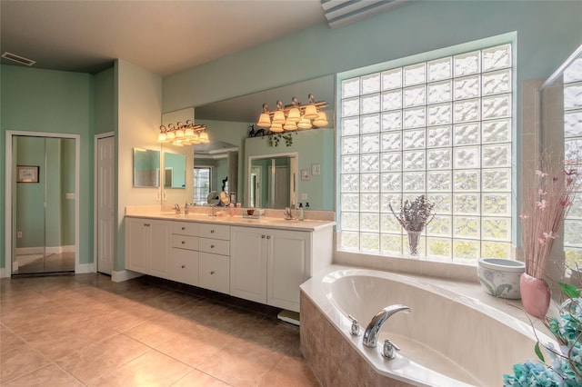 bathroom featuring tile patterned floors, vanity, and a relaxing tiled tub