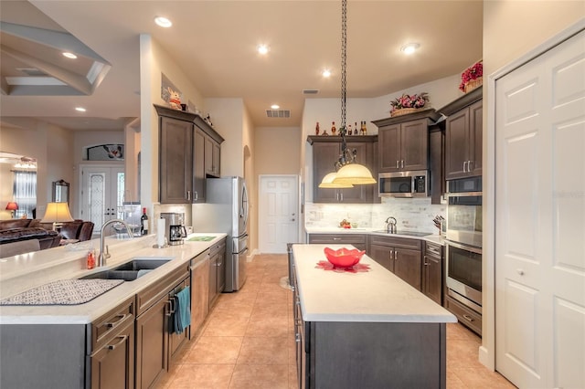 kitchen featuring appliances with stainless steel finishes, tasteful backsplash, sink, light tile patterned floors, and hanging light fixtures