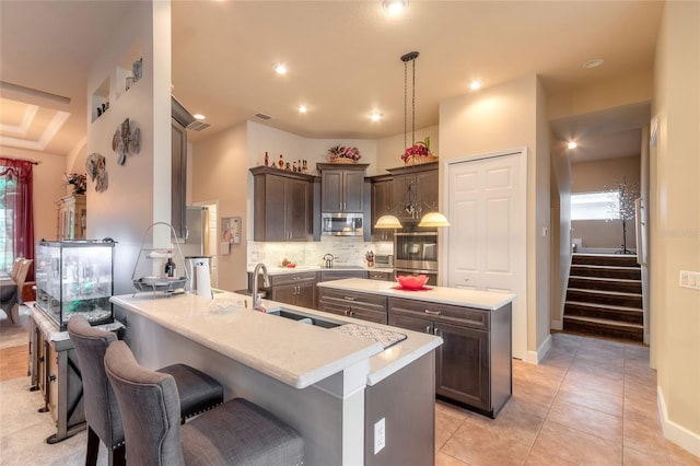 kitchen with a center island, sink, decorative light fixtures, decorative backsplash, and light tile patterned floors