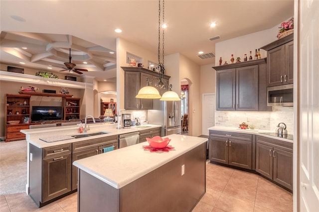 kitchen featuring kitchen peninsula, stainless steel appliances, sink, a center island, and hanging light fixtures