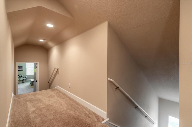 interior space with carpet flooring, a textured ceiling, and vaulted ceiling