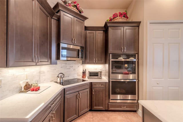 kitchen featuring light tile patterned floors, backsplash, stainless steel appliances, and dark brown cabinetry