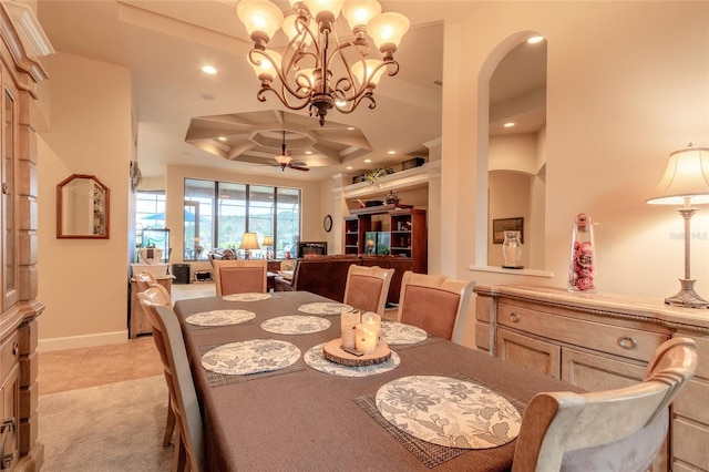 dining room with a raised ceiling, light tile patterned floors, and ceiling fan with notable chandelier