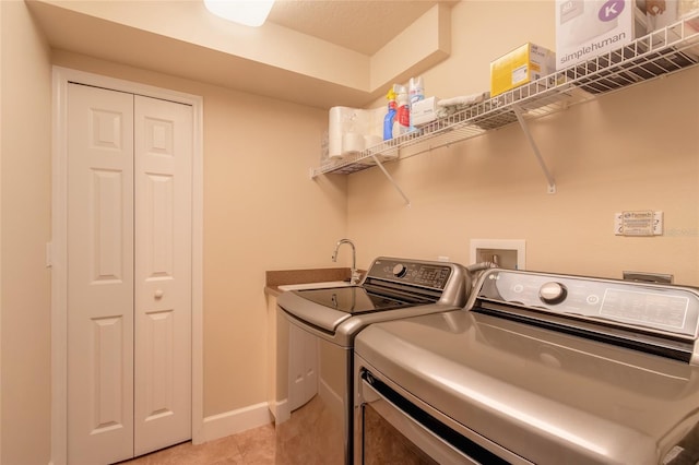 clothes washing area with washer and clothes dryer and light tile patterned floors