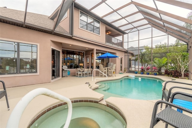 view of swimming pool featuring glass enclosure, a patio area, and an in ground hot tub