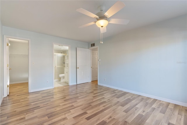 unfurnished bedroom featuring ensuite bathroom, ceiling fan, light hardwood / wood-style floors, a closet, and a walk in closet