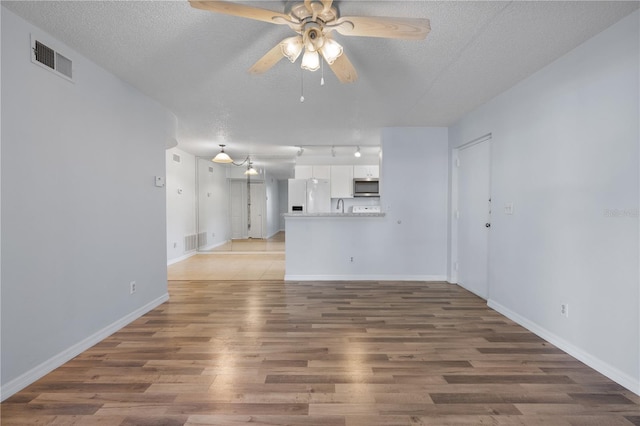 unfurnished living room featuring a textured ceiling, ceiling fan, and wood-type flooring