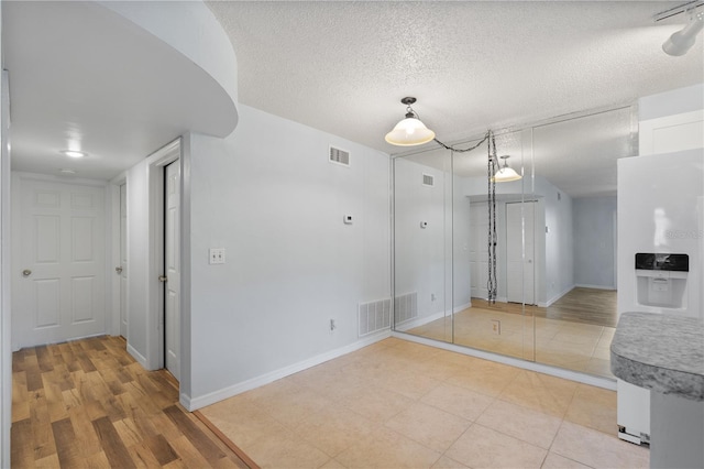 spare room with a textured ceiling and light hardwood / wood-style flooring