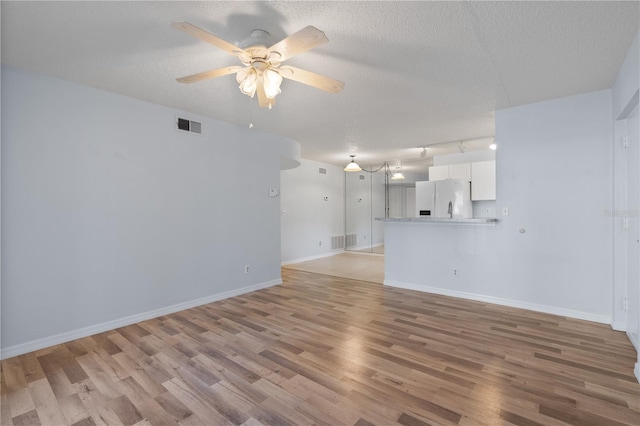 unfurnished living room featuring a textured ceiling, ceiling fan, light hardwood / wood-style flooring, and track lighting