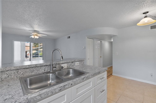 kitchen with white cabinets, a textured ceiling, and sink