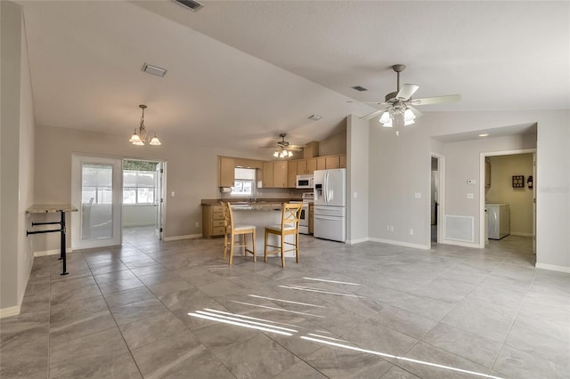 kitchen featuring a kitchen breakfast bar, washer / dryer, lofted ceiling, white appliances, and ceiling fan with notable chandelier