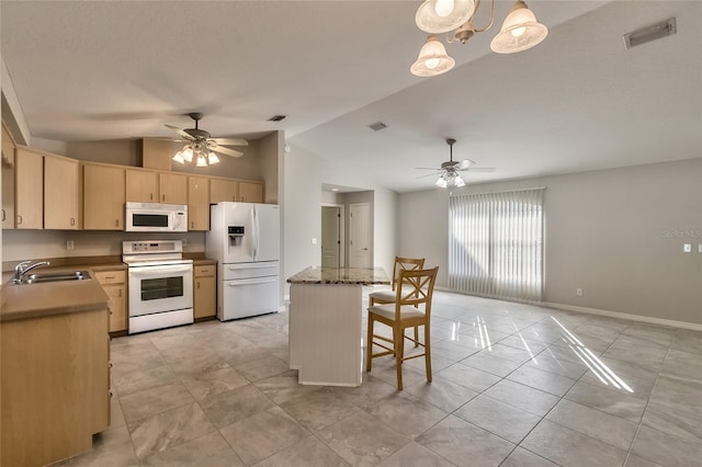 kitchen with light brown cabinets, lofted ceiling, white appliances, sink, and hanging light fixtures