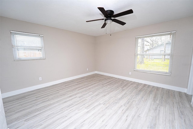 spare room with a ceiling fan, light wood-type flooring, and baseboards