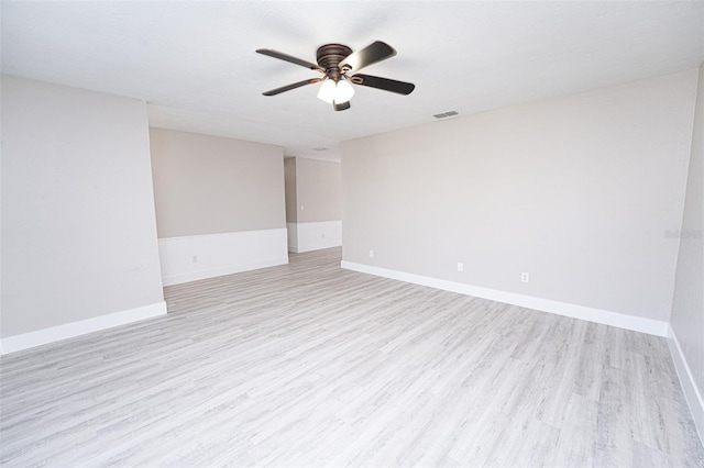 empty room featuring light wood finished floors, visible vents, and baseboards