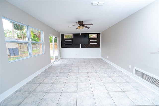 empty room with baseboards, light tile patterned floors, visible vents, and a ceiling fan