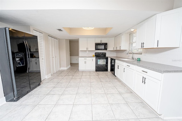 kitchen with tasteful backsplash, visible vents, a tray ceiling, black appliances, and a sink