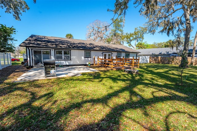 rear view of property with a yard, fence, a deck, and a patio