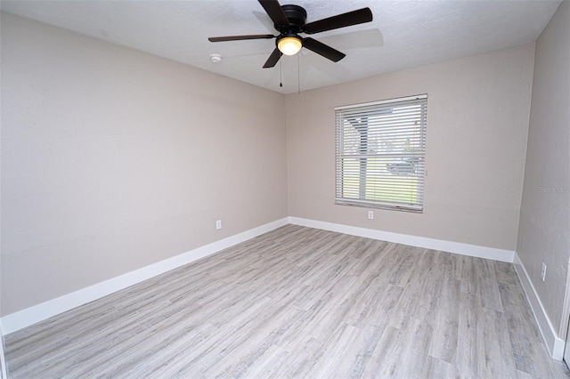 empty room with ceiling fan, a textured ceiling, baseboards, and wood finished floors