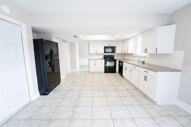 kitchen featuring white cabinets, decorative backsplash, a raised ceiling, black appliances, and a sink