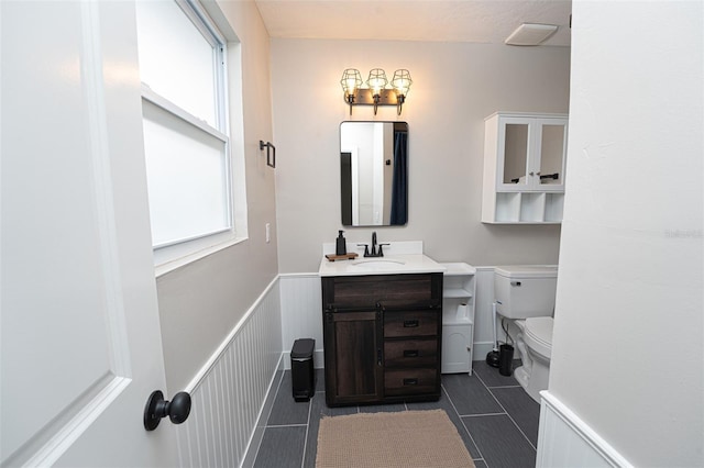 bathroom featuring a wainscoted wall, vanity, and toilet